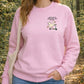 Person wearing a pink sweatshirt with a graphic and text in a forest setting