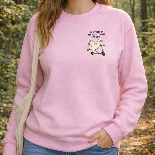 Person wearing a pink sweatshirt with a graphic and text in a forest setting