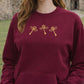 Maroon sweatshirt with gold flying keys design worn by a person outdoors.