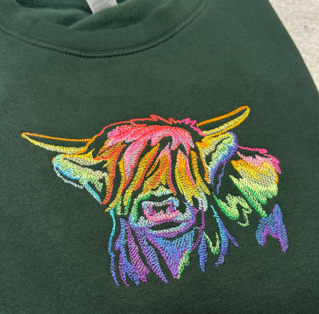 Green sweatshirt with a colourful embroidered highland cow design.