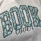 BOOK embroidered using Liberty floral fabric and appliqued onto a grey sweatshirt. The word Lover embroidered underneath.