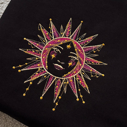 Embroidered sun and moon design on a black fabric background