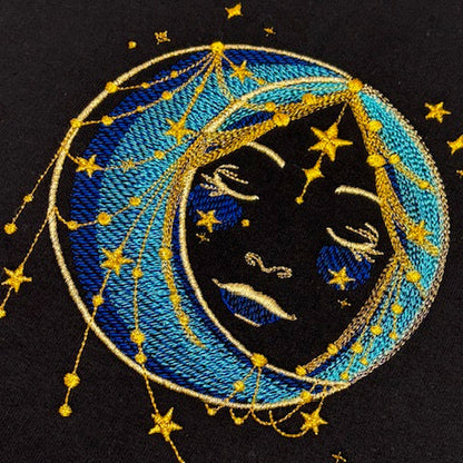 Embroidered design of a moon face within a blue circle with gold stars on a black background