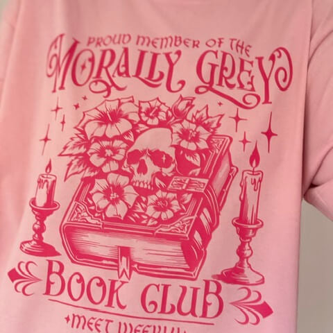 Pink t-shirt with red graphic design and text on a plain background