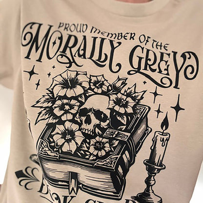 Beige sweatshirt with black graphic design featuring a skull, book, and candle, text 'Proud Member of the Morally Grey Dark Club Weekly'.