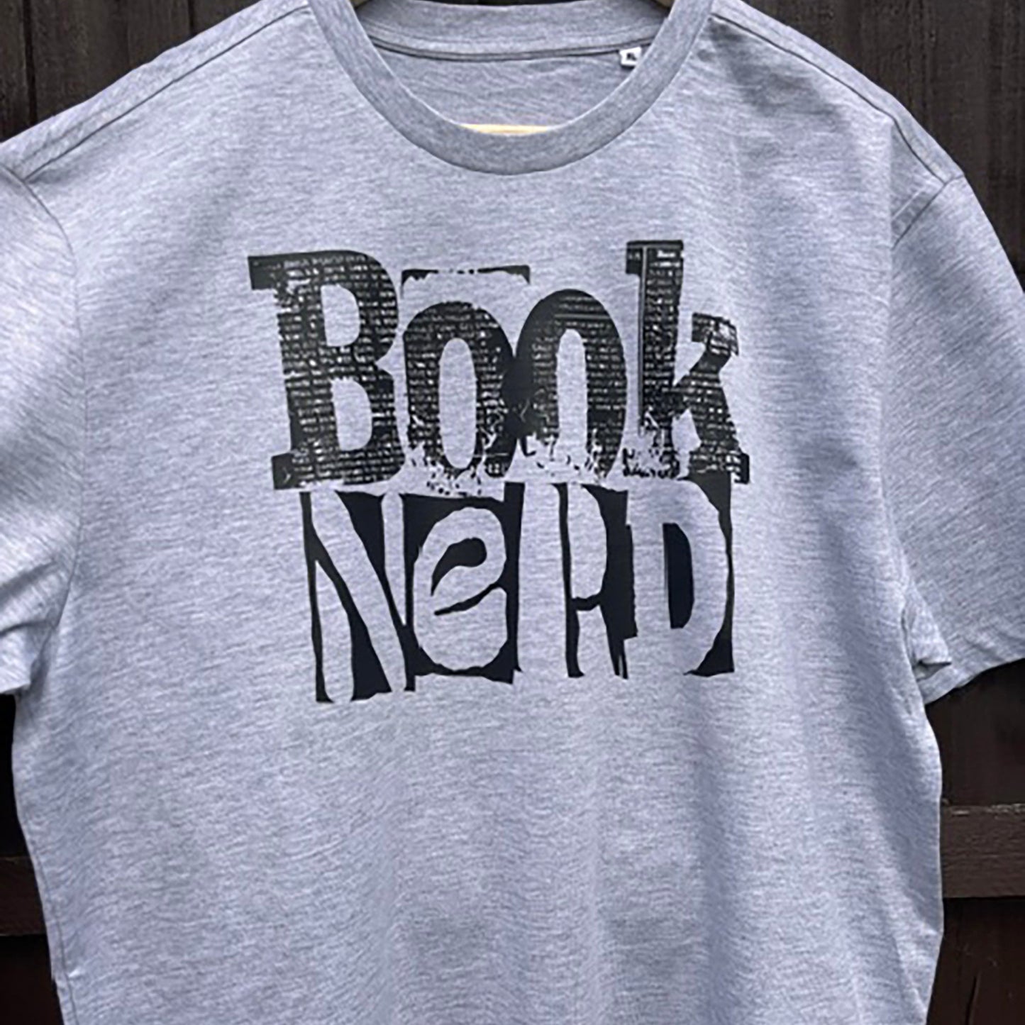 Grey t-shirt with 'Book Nerd' text on a wooden background