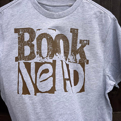 Gray t-shirt with 'Book Nerd' text in brown against a wooden background
