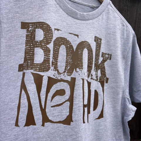 Grey t-shirt with 'Book Nerd' text in brown against a wooden background