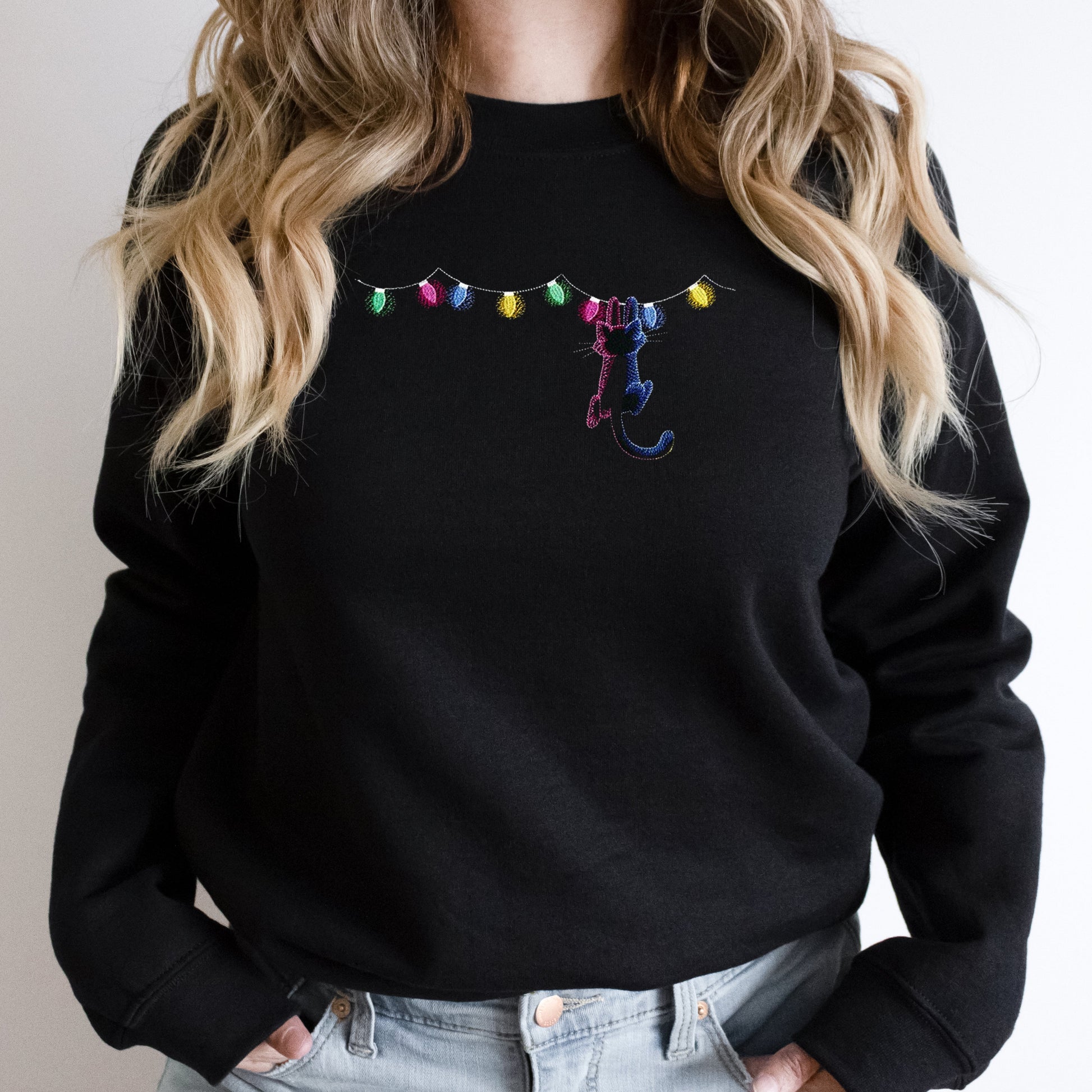 Black sweatshirt with colorful embroidered design on a plain background