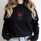 Black sweatshirt with a colorful deer design worn by a person with blonde hair.