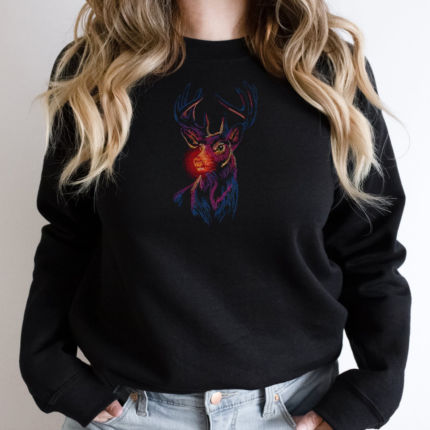 Black sweatshirt with a colorful deer design worn by a person with blonde hair.