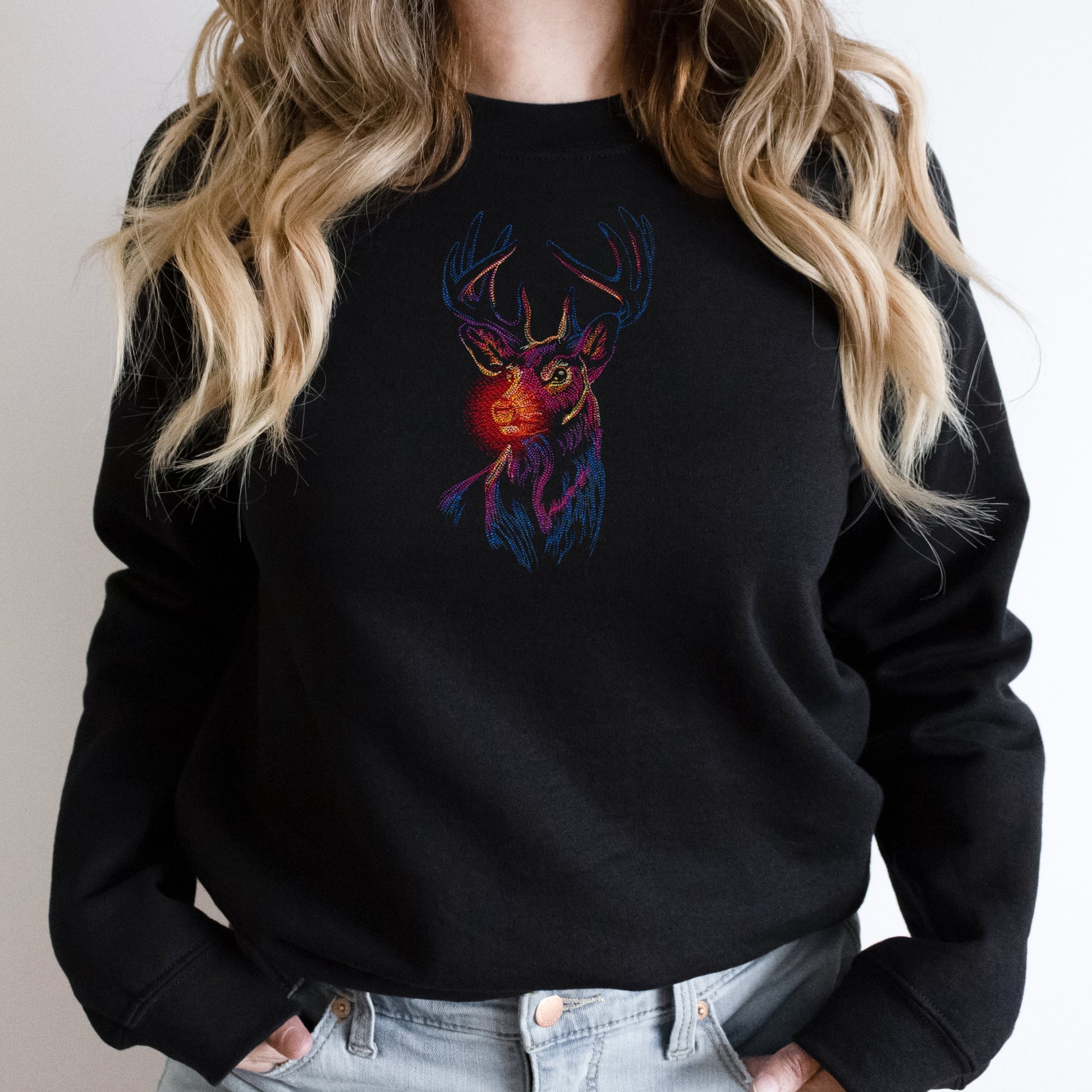 Black sweatshirt with a colorful deer design worn by a person with blonde hair.
