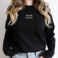 The words "Book Lover" embroidered on a black sweatshirt, worn by a girl with long blonde hair.
