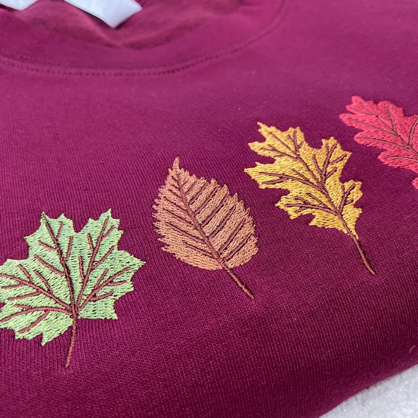 Burgundy sweatshirt with embroidered leaves in various colours 