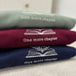 Stack of three sweatshirts with 'One more chapter' text and book illustration embroidered.