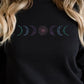 Black sweatshirt with embroidered design featuring moon phases, worn by a woman with blonde hair.