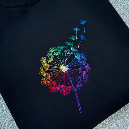 Black sweatshirt folded with a colourful embroidered dandelion clock design 