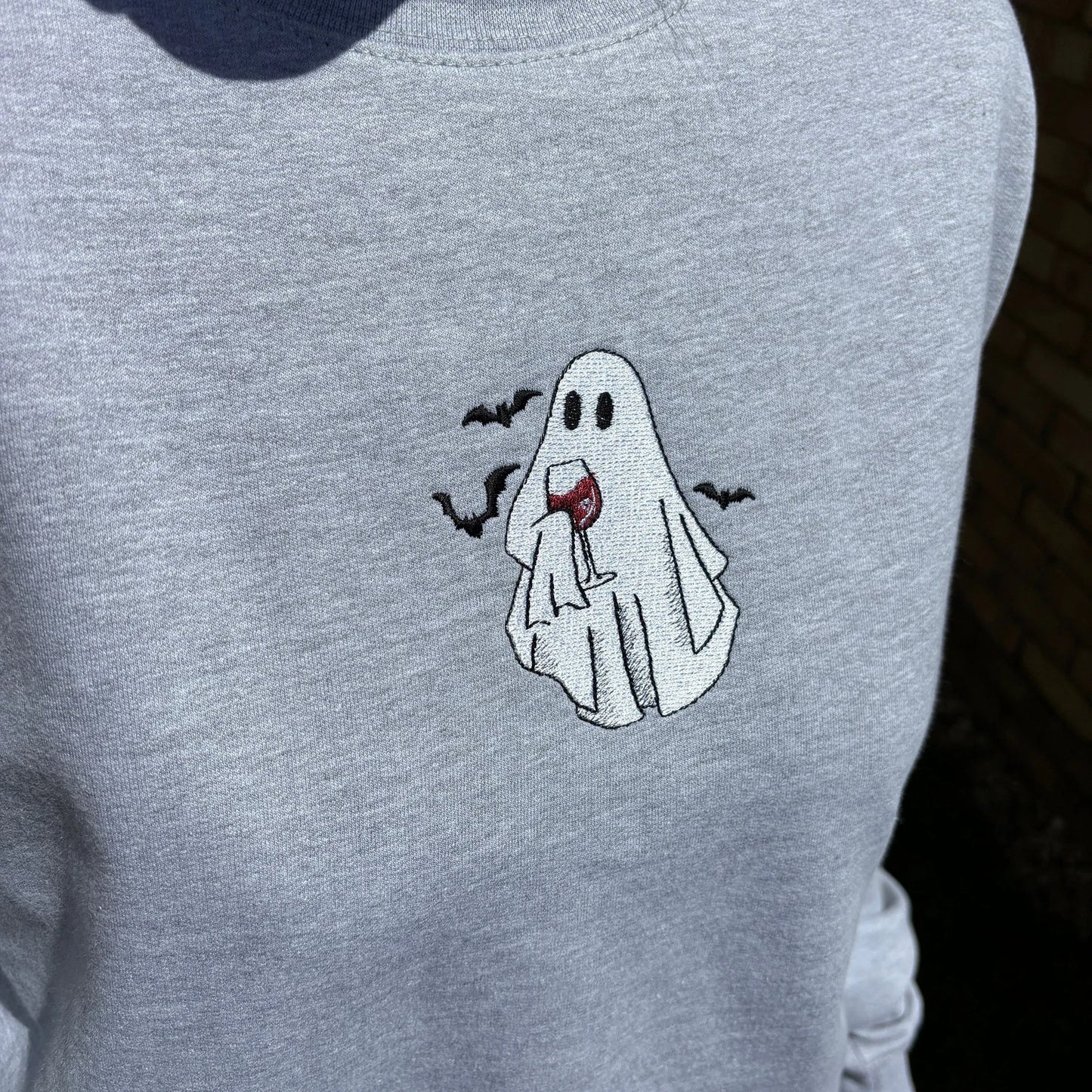 Grey sweatshirt with a ghost holding a wine glass design embroidery.