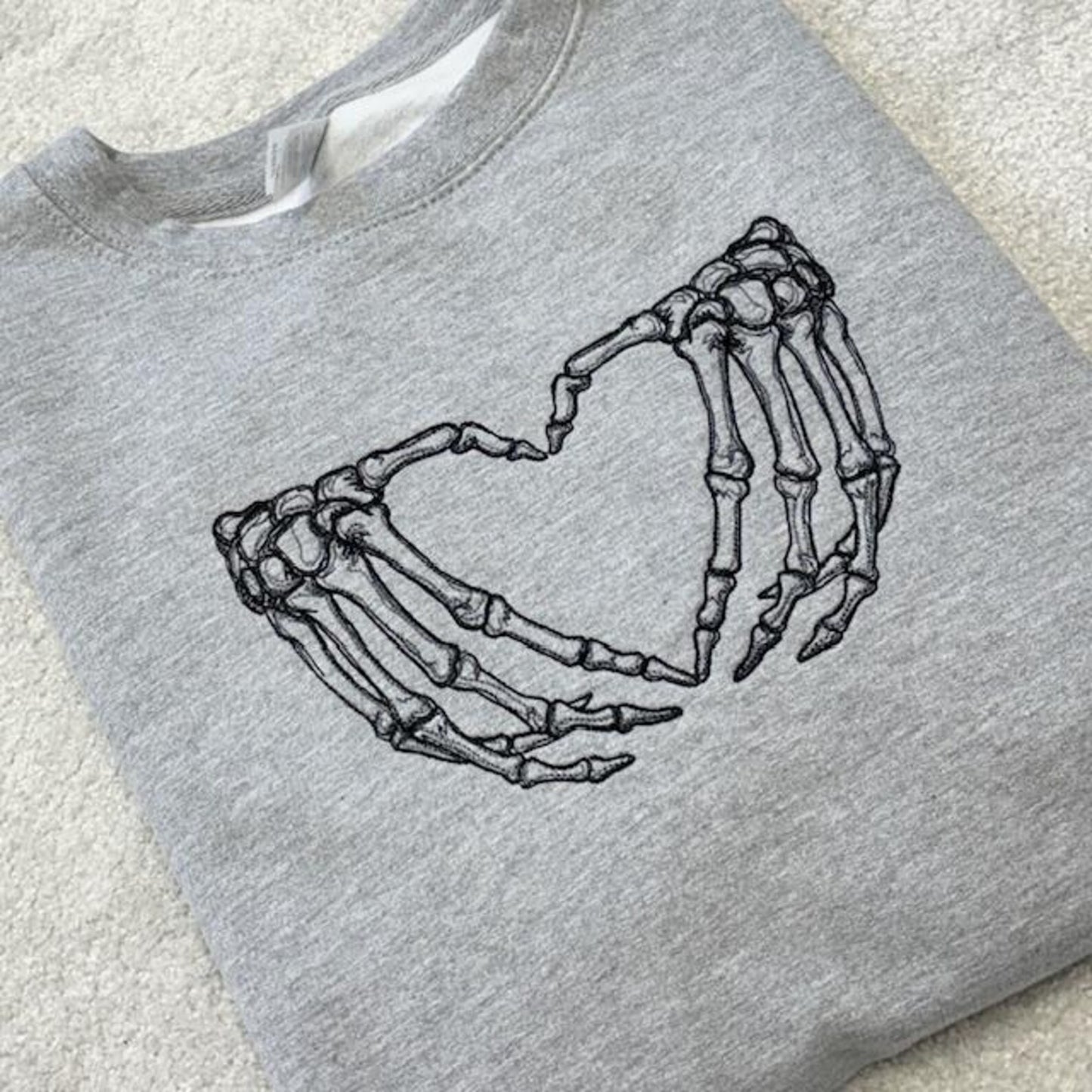 Grey sweatshirt with skeleton hands forming a heart design