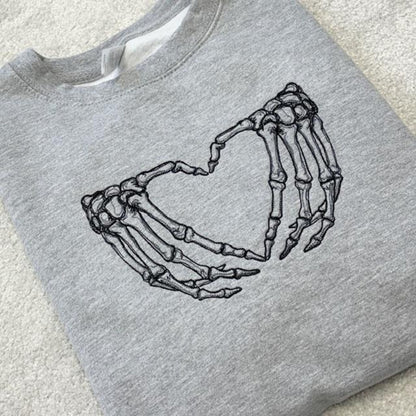 Grey sweatshirt with skeleton hands forming a heart design