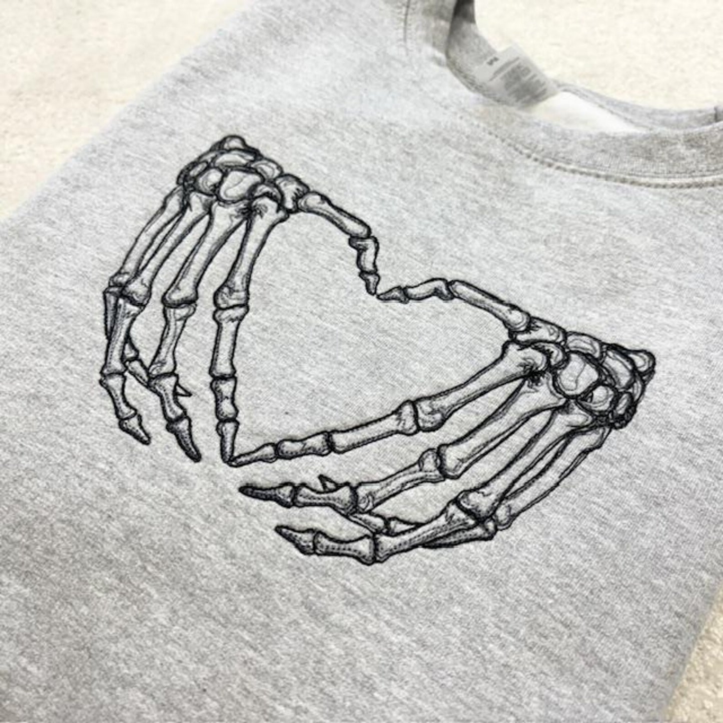 Grey sweatshirt with skeleton hands forming a heart design 