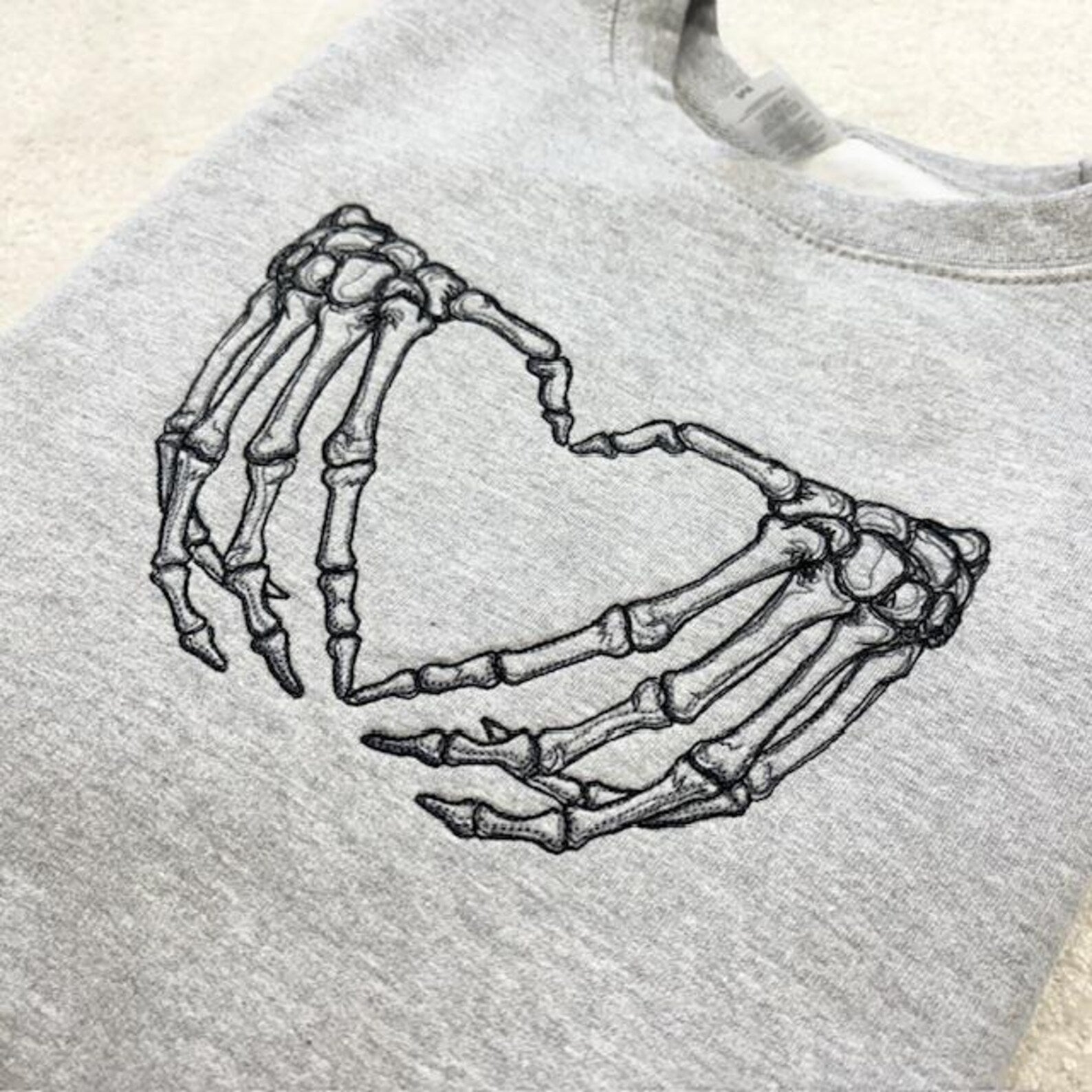 Grey sweatshirt with skeleton hands forming a heart design 