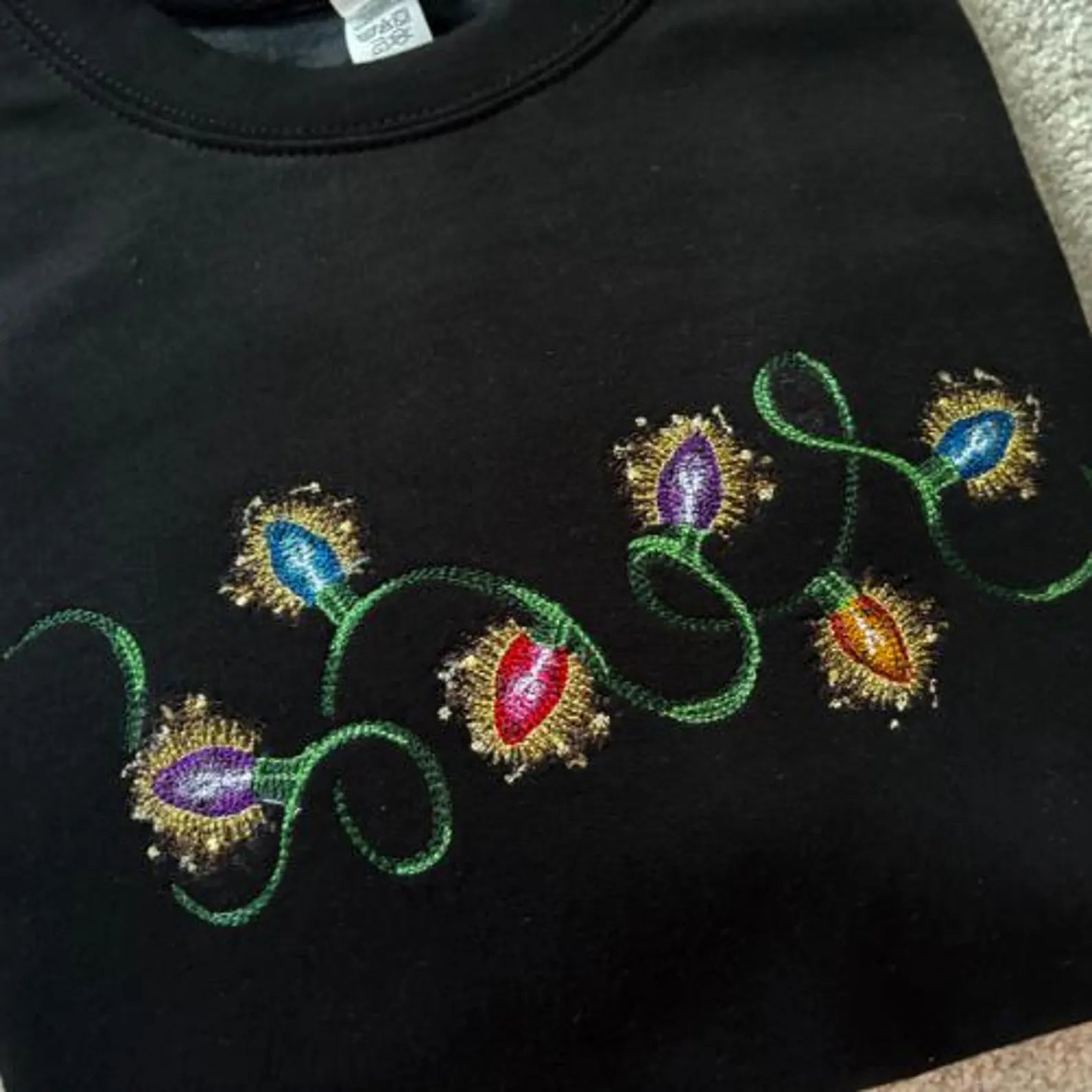 Black sweatshirt with colourful embroidered Christmas light bulbs