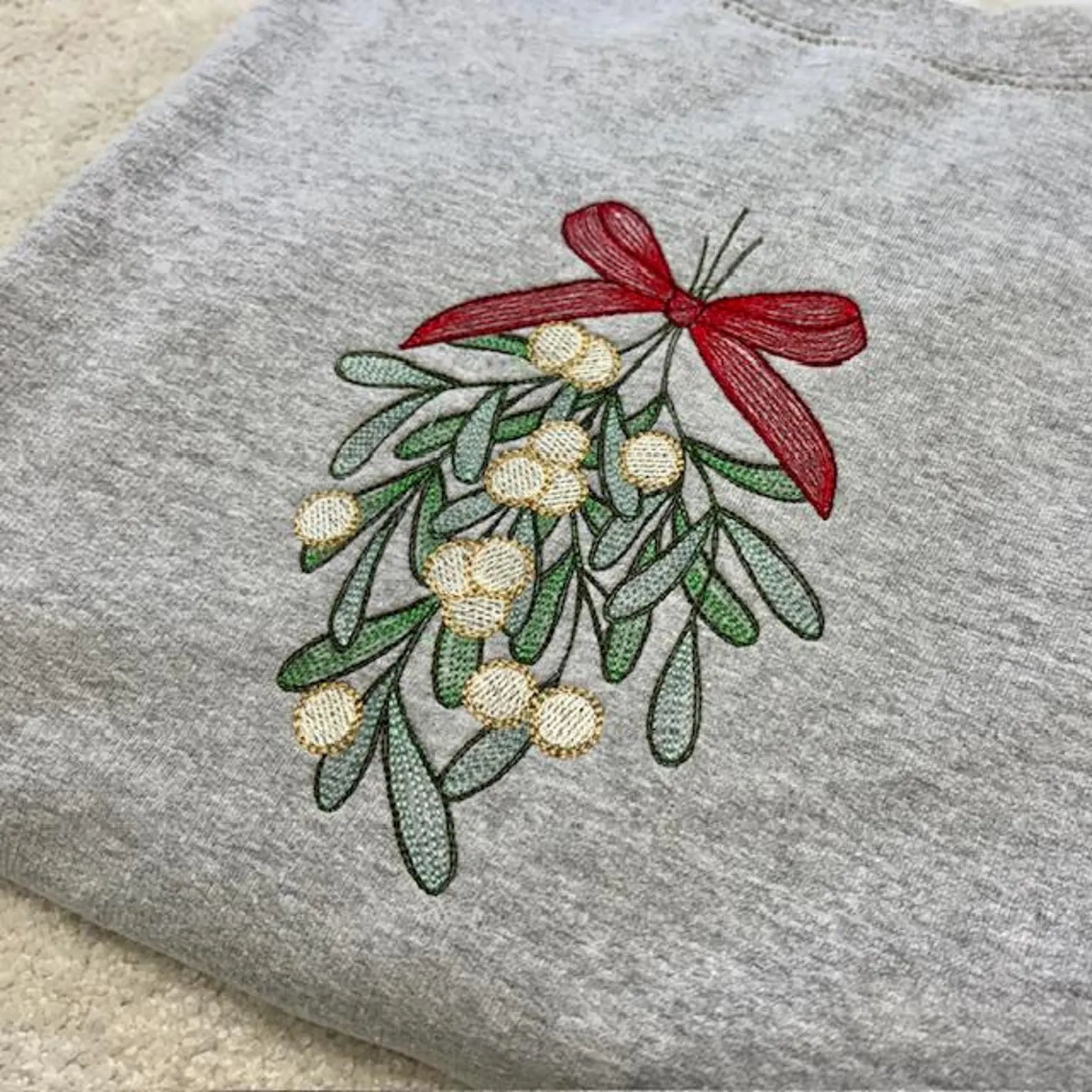 Embroidered mistletoe design with a red bow on a grey sweatshirt