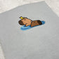Embroidered design of a capybara and a bird on a grey fabric background
