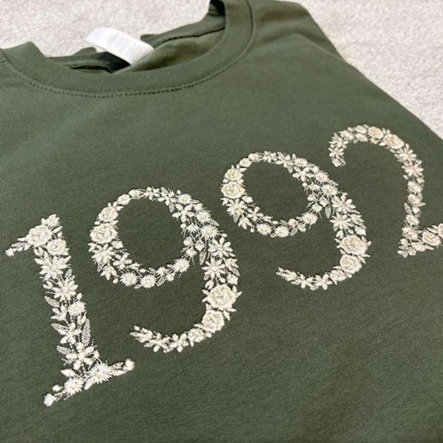 Green sweatshirt with '1992' design embroidered in a floral design on a earthy green sweatshirt