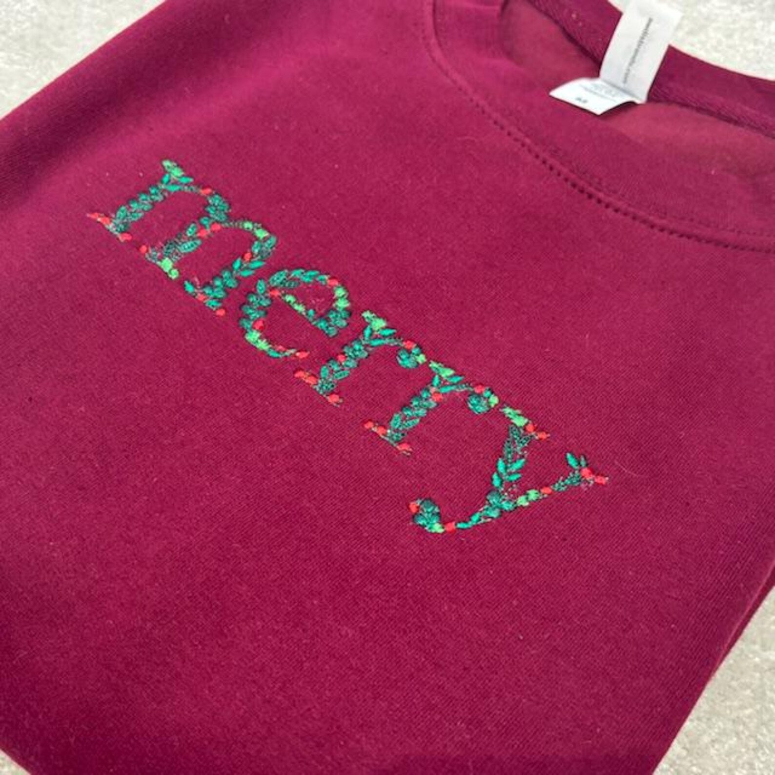 Maroon sweatshirt with 'Merry' embroidered in festive colours 