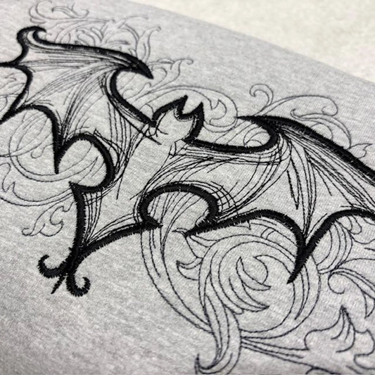 Detailed black line drawing of a gothic bat on a grey sweatshirt