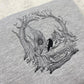 Embroidered sketch style of a skull on a grey sweatshirt