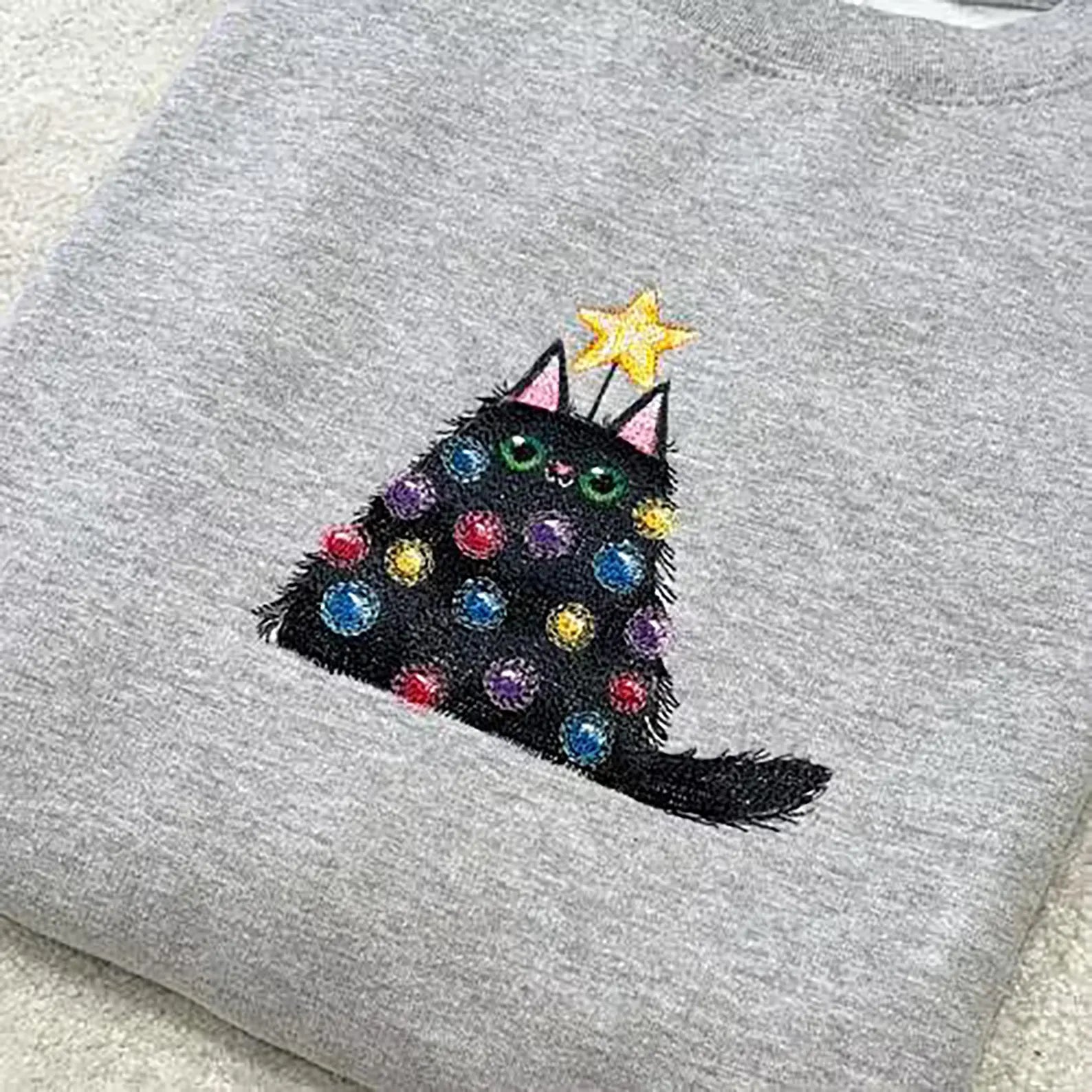 Grey sweatshirt with a black cat embroidered design featuring colourful christmas lights.