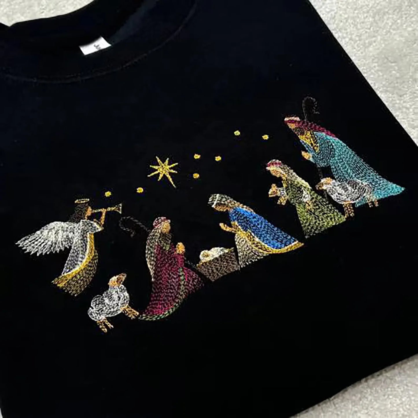 A nativity scene stitched onto a black sweatshirt. 