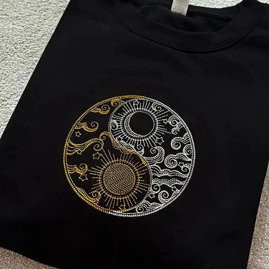 Yin Yang design embroidered in gold and silver onto a black sweatshirt.