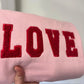 Fluffy red 'LOVE' text embroidered onto pale pink sweatshirt.